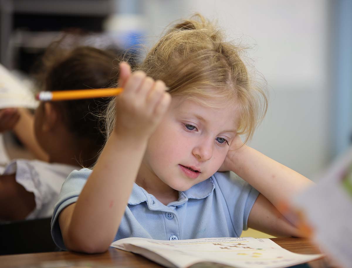 Elementary student smiling and posing together in a classroom.